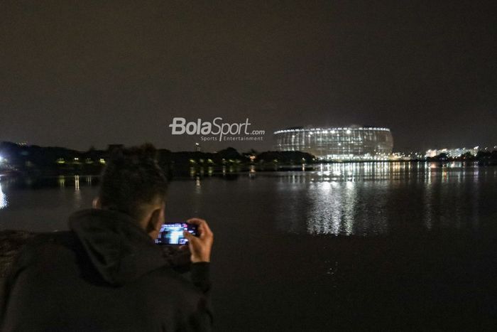 Salah satu warga sedang mengamati kemegahan Jakarta Internasional Stadium (JIS) dari Danau Cincin, Jakarta Utara, 28 September 2022.