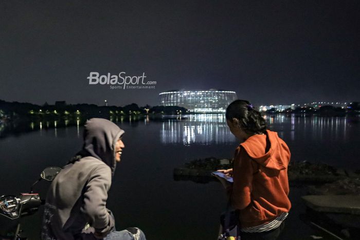 Dua sejoli sedang bercengkrama dengan pemandangan Jakarta Internasional Stadium (JIS) di Danau Cincin, Jakarta Utara, 28 September 2022.