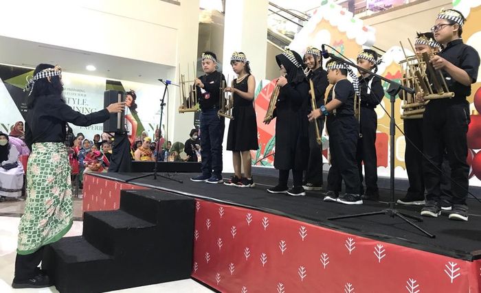 Kelompok anak inklusif, termasuk beberapa penyandang sindrom down, sedang tampi memainkan angklung di panggung.
