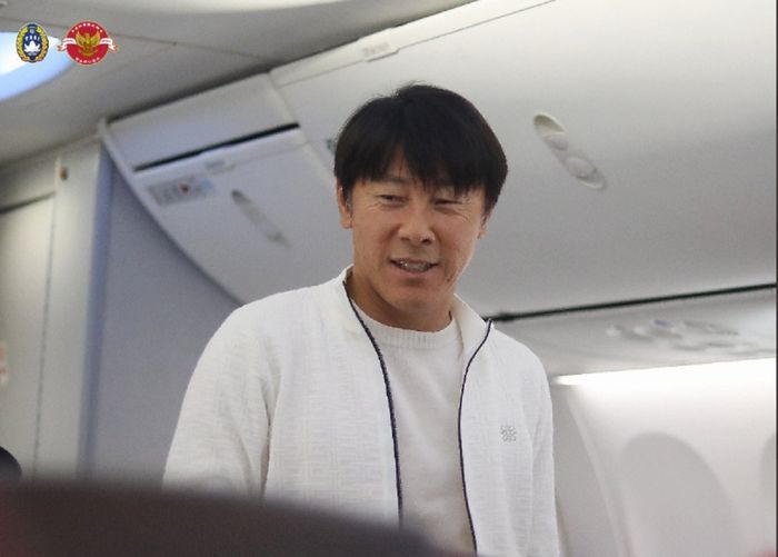 Pelatih Timnas Indonesia Shin Tae-yong tersenyum menyapa pemainnya di dalam pesawat menuju Filipina, Jumat (30/12/2022), untuk laga Piala AFF 2022.