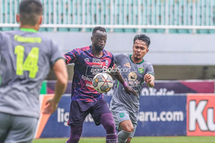 Gelandang asing RANS Nusantara FC, Makan Konate (kiri), sedang menguasai bola dan dijaga ketat pemain Persebaya Surabaya bernama Muhammad Hidayat (kanan) dalam laga pekan ke-27 Liga 1 2022 di Stadion Pakansari, Bogor, Jawa Barat, Selasa (28/2/2023).