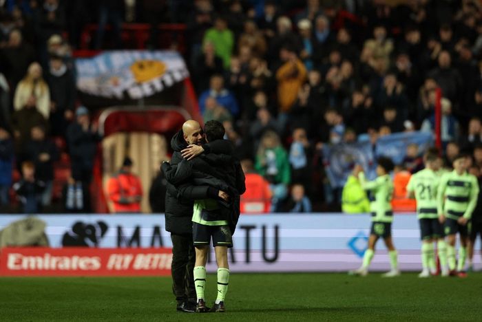 Pelatih Manchester City, Pep Guardiola, memeluk Bernardo Silva seusai laga ronde kelima Piala FA kontra Bristol City di Stadion Ashton Gate, Selasa (28/2/2023).