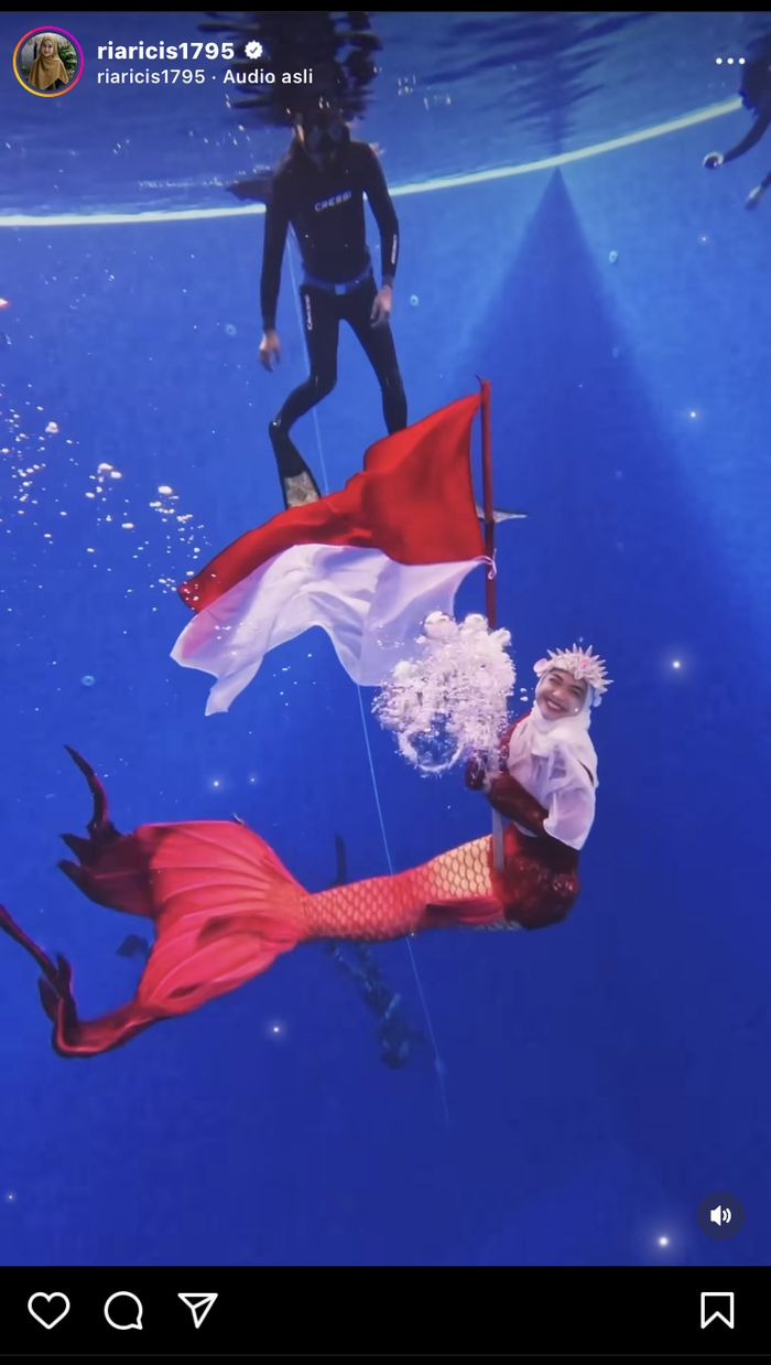 Ria Ricis kibarkan bendera di dalam air dengan kostum mermaid.