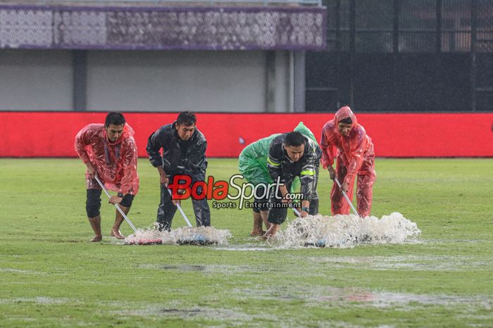 Sejumlah petugas sedang membereskan genangan air yang menggenang seusai Laga pekan ke-22 Liga 1 2023 antara Dewa United versus Bali United sempat terpaksa ditunda sementara karena cuaca hujan dan petir di Stadion Indomilk Arena, Tangerang, Banten, Jumat (8/12/2023).