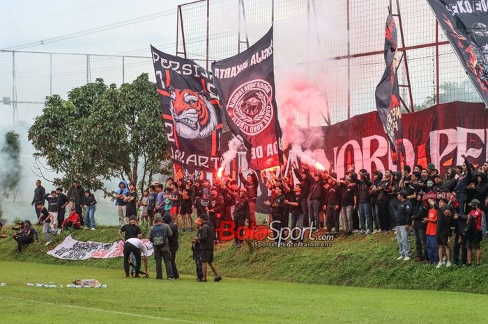 Sejumlah The Jakmania tampak memberikan semangat dan menyalakan flare saat tim kesayangannya yakni Persija Jakarta berlatih di Lapangan Nirwana Park, Sawangan, Jawa Barat, Rabu (6/3/2024).