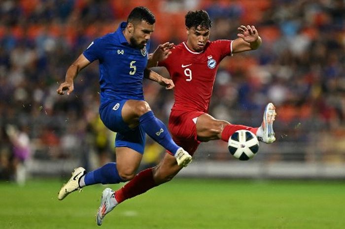 Kritsada Kaman (Kiri) dari Thailand dan Ikhsan Fandi (kanan) dari Singapura berebut bola saat laga Kualifikasi Piala Dunia 2026 antara Thailand Vs Singapura di Stadion Rajamangala, Bangkok pada Selasa 11 Juni 2024.