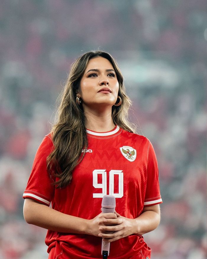 Raisa mengenakan baju timnas Indonesia berwarna merah saat bernyanyi di GBK.