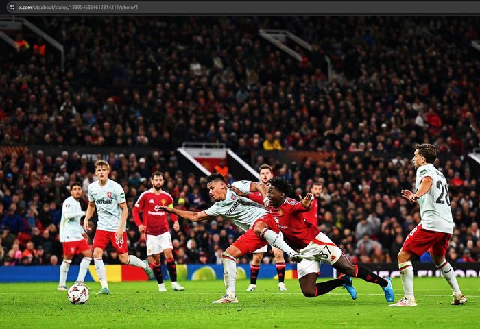 Aksi bek FC Twente berdarah Indonesia, Mees Hilgers, menjatuhkan Kobbie Mainoo dalam laga melawan Manchester United pada matchday 1 Liga Europa 2024-2025 di Stadion Old Trafford, Rabu (25/9/2024).