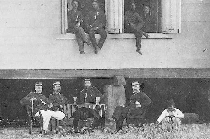 Potret para prajurit Belanda bersama dengan djongos (jongkok paling kanan) di gedung kantin, tampak gelas jenever.