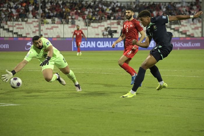 Australia's forward #9 Kusini Yengi shoots to score his team's first goal past Bahrain's goalkeeper #22 Ebrahim Lutfalla during the FIFA World Cup 2026 Asia zone qualifiers group C football match between Bahrain and Australia at Bahrain National Stadium in Riffa on November 19, 2024. (Photo by Mazen