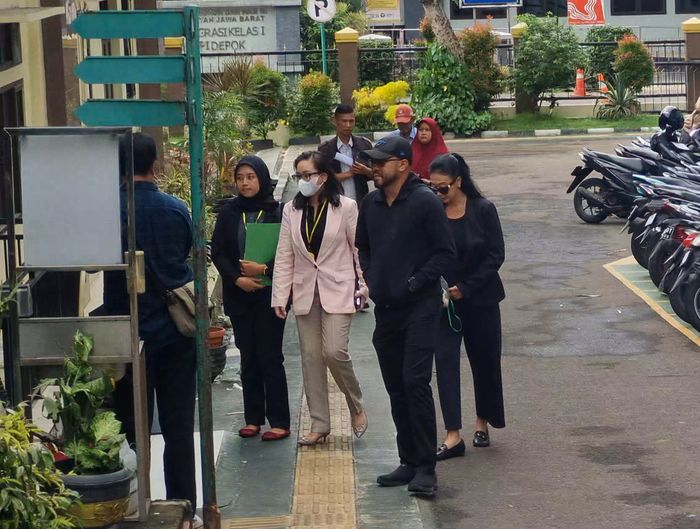  Suami Asri Welas tampil mengenakan jaket, celana, dan topi hitam serasi dengan sang aktris.