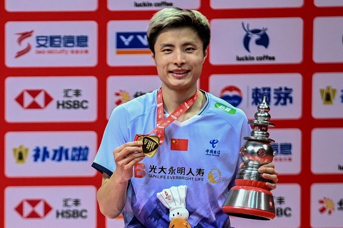 Pebulu tangkis tunggal putra China, Shi Yu Qi, berpose dengan trofi juara BWF World Tour Finals 2024 di Hangzhou Olympic Sports Centre Gymnasium, Minggu (15/12/2024).