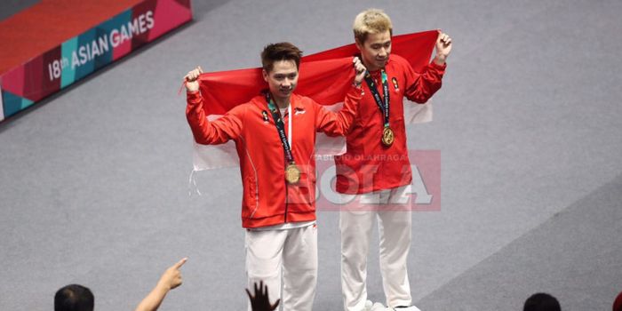 Marcus Fernaldi Gideon (kanan) dan Kevin Sanjaya Sukamuljo (kiri) membentangkan bendera Merah Putih seusai menjuarai nomor ganda putra pada Asian Games 2018.