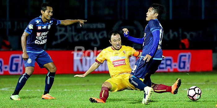 Aksi gelandang Sriwijaya FC, Yu Hyun-koo (tengah), saat melakukan tekel kepada pemain Arema FC dalam