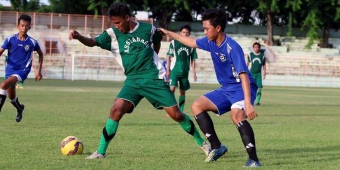 Pemain Assyabaab (hijau) berusaha melindungi bola dari pilar Colombo FC di Gelora 10 November, Surab