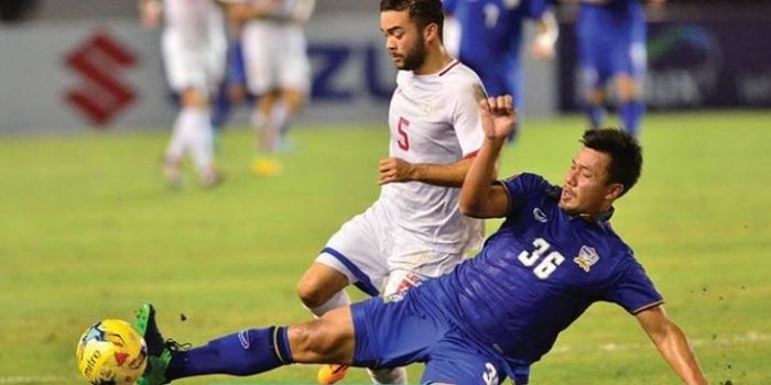 Pemain Thailand, Prakit Deprom (biru) berebut bola dengan gelandang Filipina, Mike Ott di Philipinne