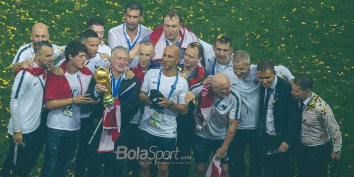  Pelatih Prancis, Didier Deschamps, memegang  trofi juara Piala Dunia 2018 didampingi stafnya.