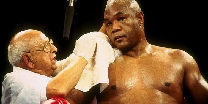 George Foreman (kanan), mendapat perawatan dari timnya dalam pertandingan terakhirnya di dunia tinju