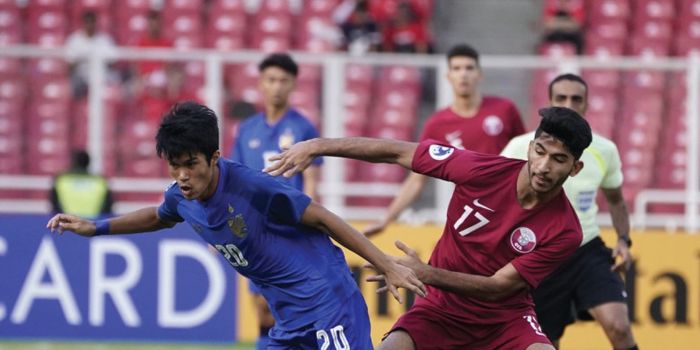 Pemain tengah timnas U-19 Thailand, Airfan Doloh (kiri) berebut bola dengan pemain timnas U-19 Qatar