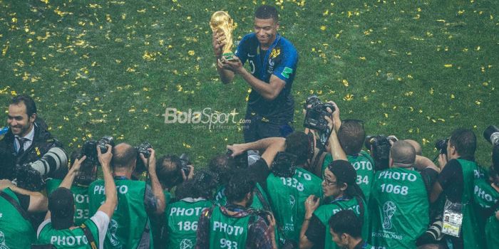 Penyerang Prancis, Kylian Mbappe, berpose dengan trofi juara Piala Dunia 2018. Mbappe menegaskan ingin bertahan di PSG di tengah rumor transfer ke Real Madrid.