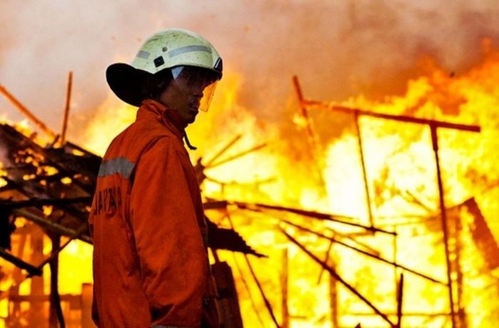 Petugas Pemadam Kebakaran dan Penanggulangan Bencana Provinsi DKI Jakarta sedang memadamkan kebakaran hebat di suatu perkampungan padat.