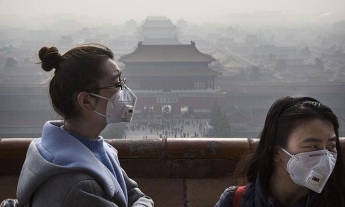 Wanita Cina memakai masker karena kabut asap yang disebabkan oleh polusi udara.