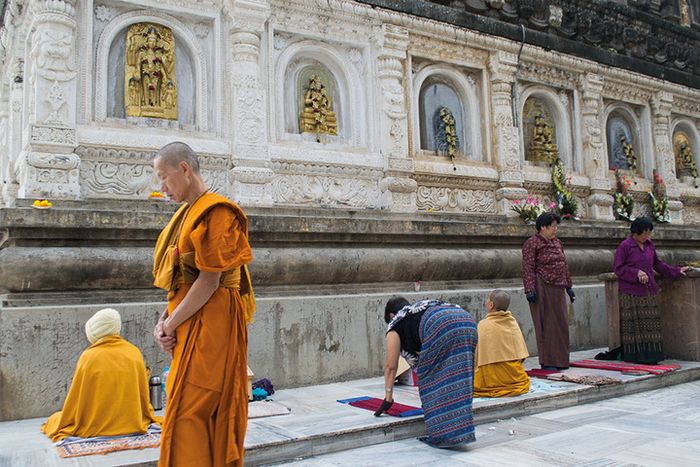 Peziarah bermeditasi di kuil utama Mahabodhi. Tampak seorang biksu melintas, yang berjalan searah jam.