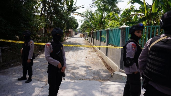 Petugas Densus 88 sedang menjaga jalan di sekitar rumah terduga teroris. 