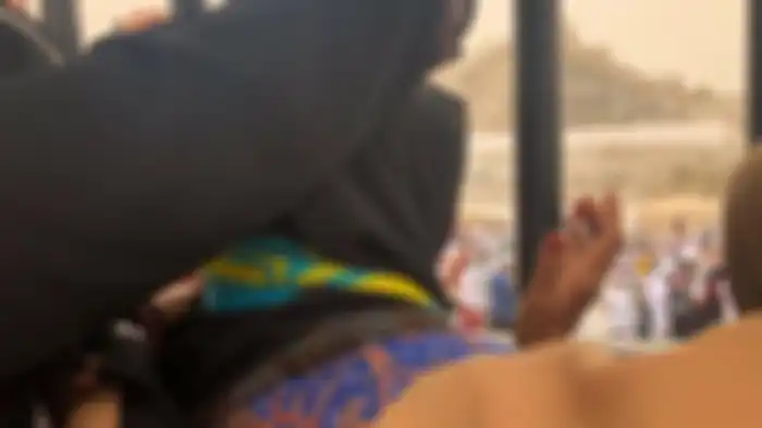Nyai Heni Maryam saat menyaksikan pemakaman suaminya KH Maimoen Zubaer dari balik pagar besi pemakaman Ma’la. Nyai Heni dilarang mendekat ke pusara Mbah Moen karena aturan di Arab Saudi yang melarang perempuan masuk ke makam. 