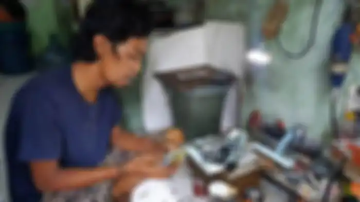 Wawang Kurniawan (38) sedang membuat potongan-potong material miniatur motor yang terbuat dari barang rongsokan.