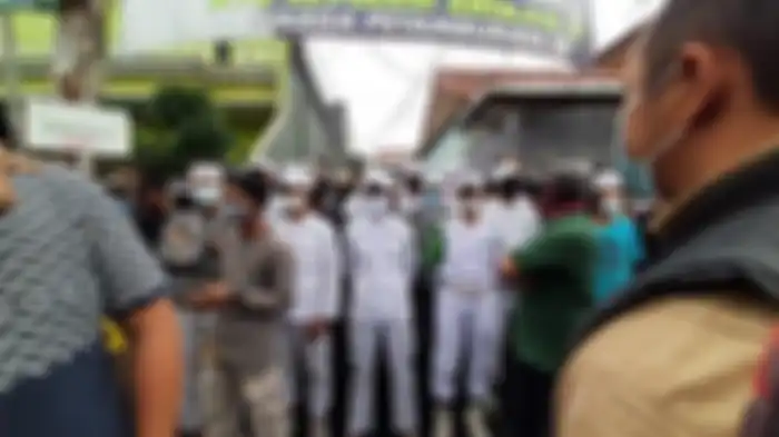 Sejumlah orang berpakain putih menghalang-halangi polisi yang hendak menyampaikan surat pemanggilan kepada Rizieq Shihab di Petamburan, Minggu (29/11/2020) sore. 