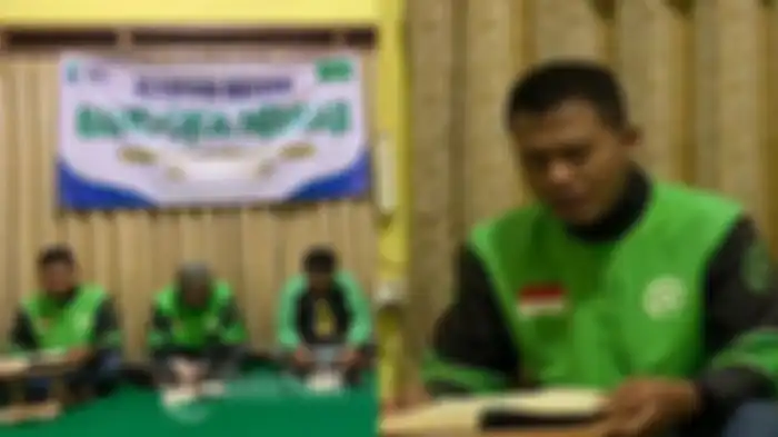 Siswanto yang sedang mengaji sambil menunggu orderan. 