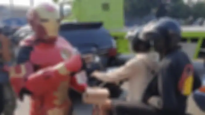 Polisi libatkan maskot Ironman dan pahlawan super di kegiatan bagi-bagi makanan di pos penyekatan Sasak Jarang Bekasi, Jumat (16/7/2021). 