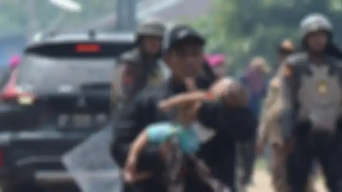 Herman menggendong bayinya yang pingsan di tengah bentrokan warga Rempang dan aparat gabungan di Jembatan 4 Barelang, Batam, Kamis (7/9/2023). Bayinya pingsan karena gas air mata masuk ke dalam rumahnya lewah jendela yang terbuka. 