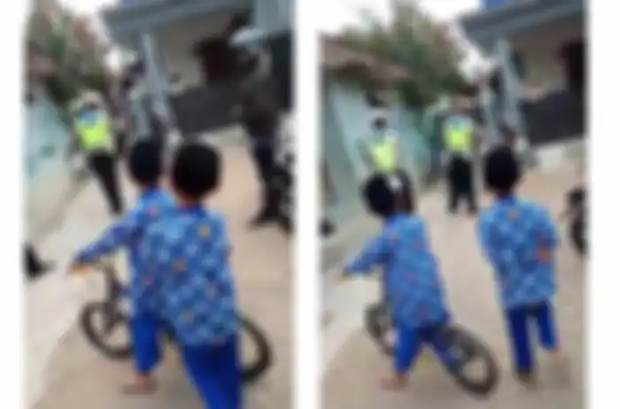 Para warga menyaksikan polisi melakukan razia di gang sempit