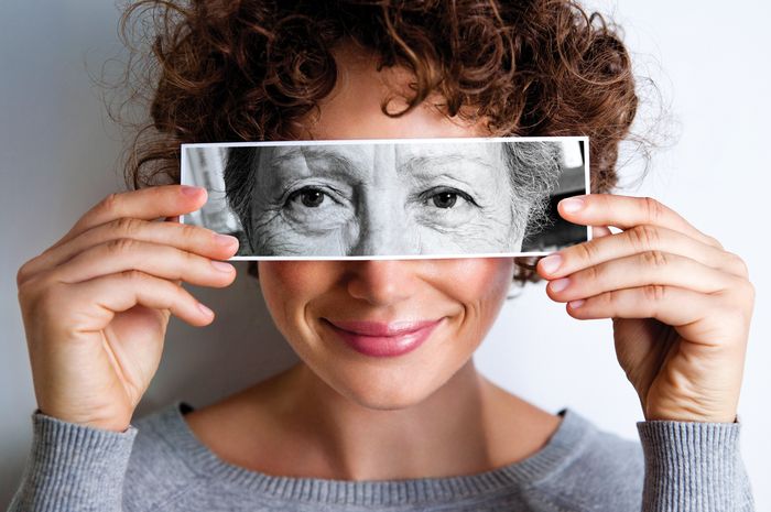 Woman with photo of elderly woman's eyes on hers'