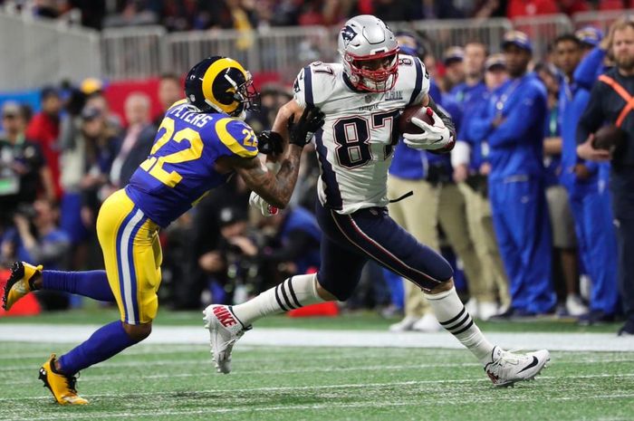 Aksi pemain New England Patriots, Rob Gronkowski (jersey putih), saat berusaha melewati penjagaan pemain Los Angeles Rams, Marcus Peters (biru, dalam laga Super Bowl 2019, Senin (4/2/2019) pagi WIB.