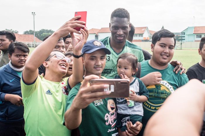 Penyerang anyar Persebaya Surabaya, Amido Balde, melayani sesi foto suporter.