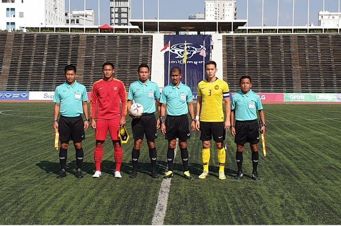 Kapten timnas U-22 Indonesia, Andy Setyo Nugroho, bersama perangkat pertandjngan dan kapten Malaysia, Dominic Tan sebelum laga Piala AFF U-22 2019 di Stadion Nasional, Phnom Penh, Rabu (20/2/2019).