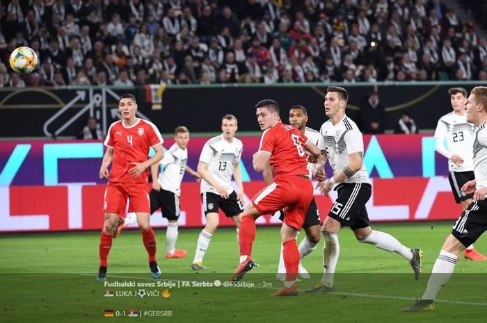 Penyerang timnas Serbia, Luka Jovic (jersey merah, tengah), mengarahkan bola dengan sundulan ke arah gawang Jerman pada laga persahabatan, Kamis (21/3/2019), di Volkswagen Arena, Wolsburg.