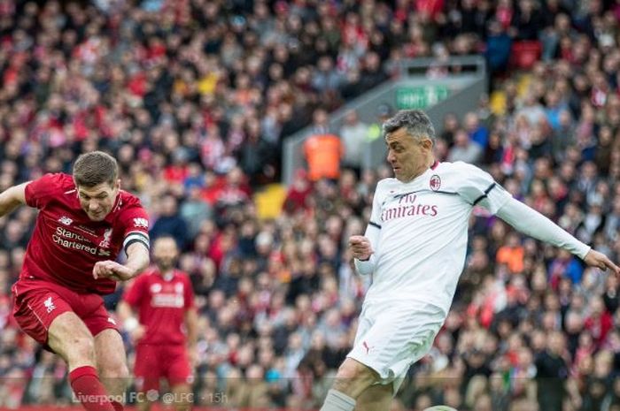 Legenda Liverpool, Steven Gerrard, diadang eks pemain AC Milan, Angelo Carbone, dalam laga amal di Stadion Anfield, Sabtu (23/3/2019).