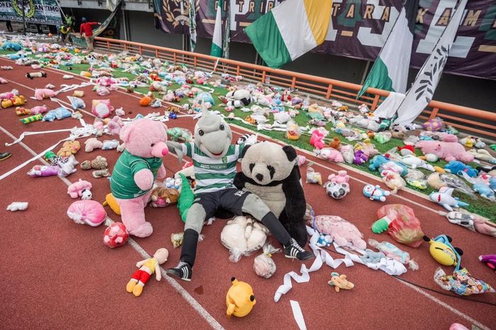 Maskot Persebaya berfoto dengan boneka-boneka yang dilemparkan oleh bonek.