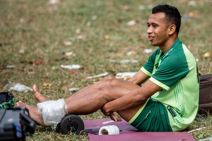 Winger Persebaya Surabaya, Irfan Jaya, mendapatkan perawatan sembari menyaksikan rekan-rekannya menjalani recovery training di Lapangan Bromo Kalinegoro Mertoyudan, Magelang, Minggu (21/9/2019).