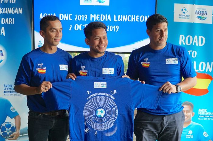 Marketing Manager Danone-Aqua, Jeffri Ricardo (kiri) bersama alumni DNC, Andik Vermansah, dan pelatih Alfredo Vera menunjukkan t-shirt Semangatmu Seragamku yang membawa harapan masyarakat Indonesia untuk anak-anak Indonesia yang akan bertanding ke Final Dunia DNC 2019, 2 Oktober 2019.