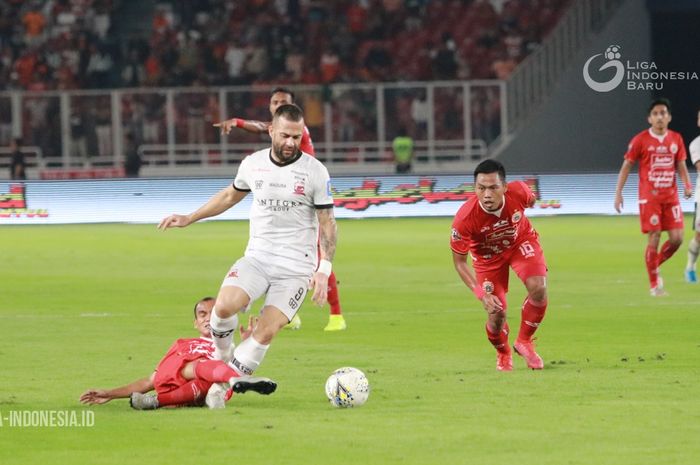 Striker asing Madura United, Alexandar Rakic (jersey putih), berduel dengan winger Persija Jakarta, Riko Simanjuntak, dalam laga pekan ke-32 di Stadion Utama Gelora Bung Karno, Jakarta Pusat, Jumat (13/12/2019).