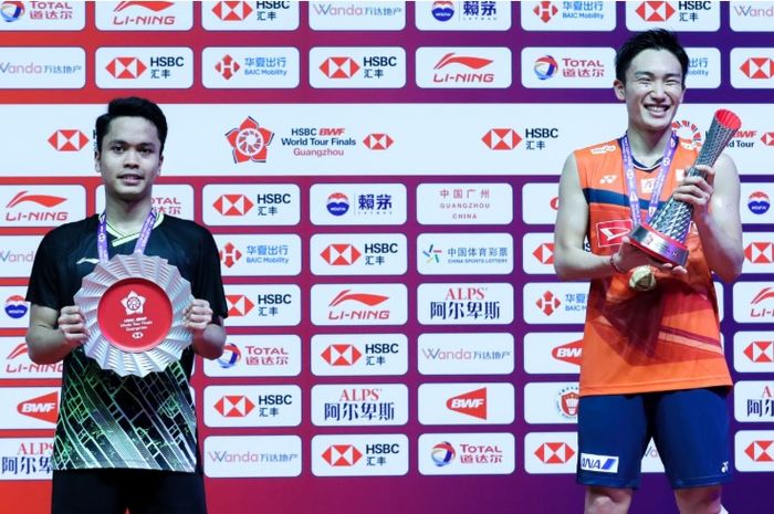 Anthony Sinisuka Ginting (kiri) dan Kento Momota (kanan) keduanya menerima piala setelah berjuang di final BWF World Tour Finals 2019 di Tianhe Gymnasium, Guangzhou, China, Minggu (15/12/2019).