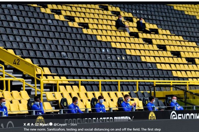 Para pemain cadangan Borussia Dortmund duduk dengan jarak renggang satu sama lain.