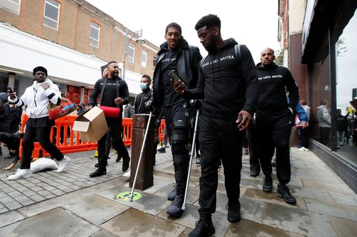 Petinju kelas berat Inggris, Anthony Joshua, terlihat memakai kruk dan penyangga di lutut kirinya saat tengah melakukan aksi protes melawan rasisme dengan tema Black Lives Matter di Watford, Inggris, Sabtu (6/6/2020).