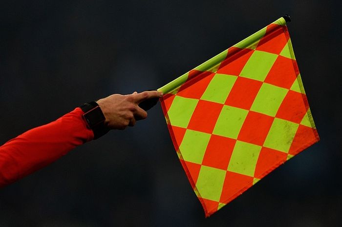 Asisten wasit mengangkat bendera tanda off-side. 