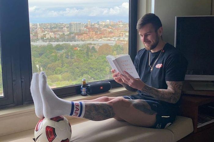 Bek PSS Sleman, Aaron Evans tengah menikmati membaca salah satu buku favoritnya.